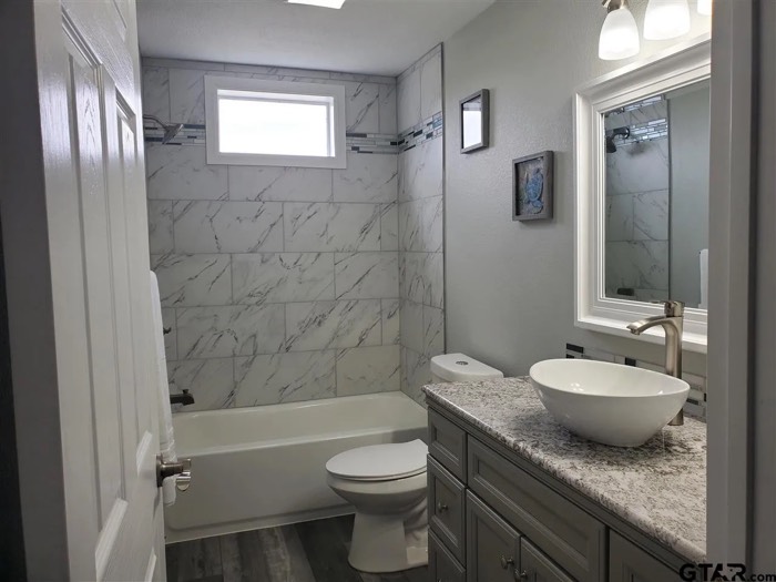 Hall bathroom with tiled tub surround and vessel sink