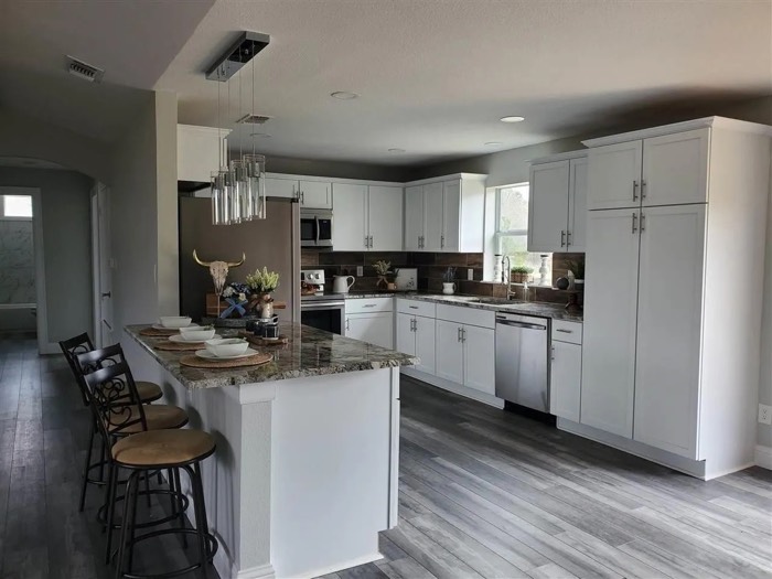 Kitchen with white shaker cabinets and a granite island